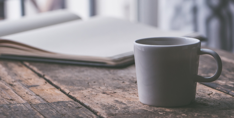 open journal on a table with a mug