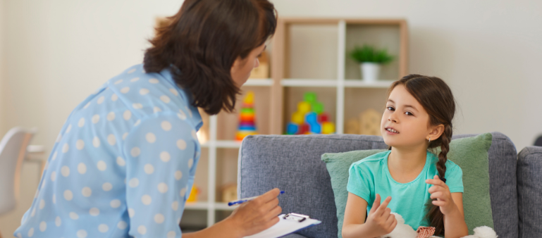 a psychologist speak with a young girl to assess, sitting with a clipboard (adhd assessment)