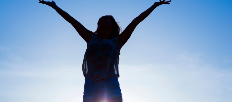 picture of silhouette of woman hands outstretched up in front of sky and clouds